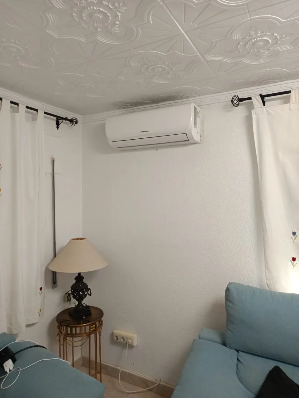 Aire acondicionado split instalado sobre el sofá de un salón.