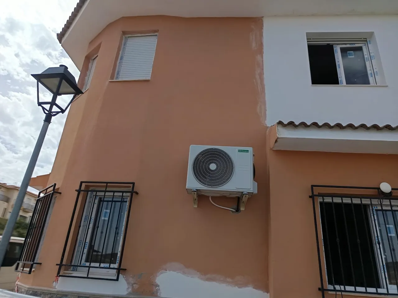 Unidad exterior de aire acondicionado en la fachada de una casa.
