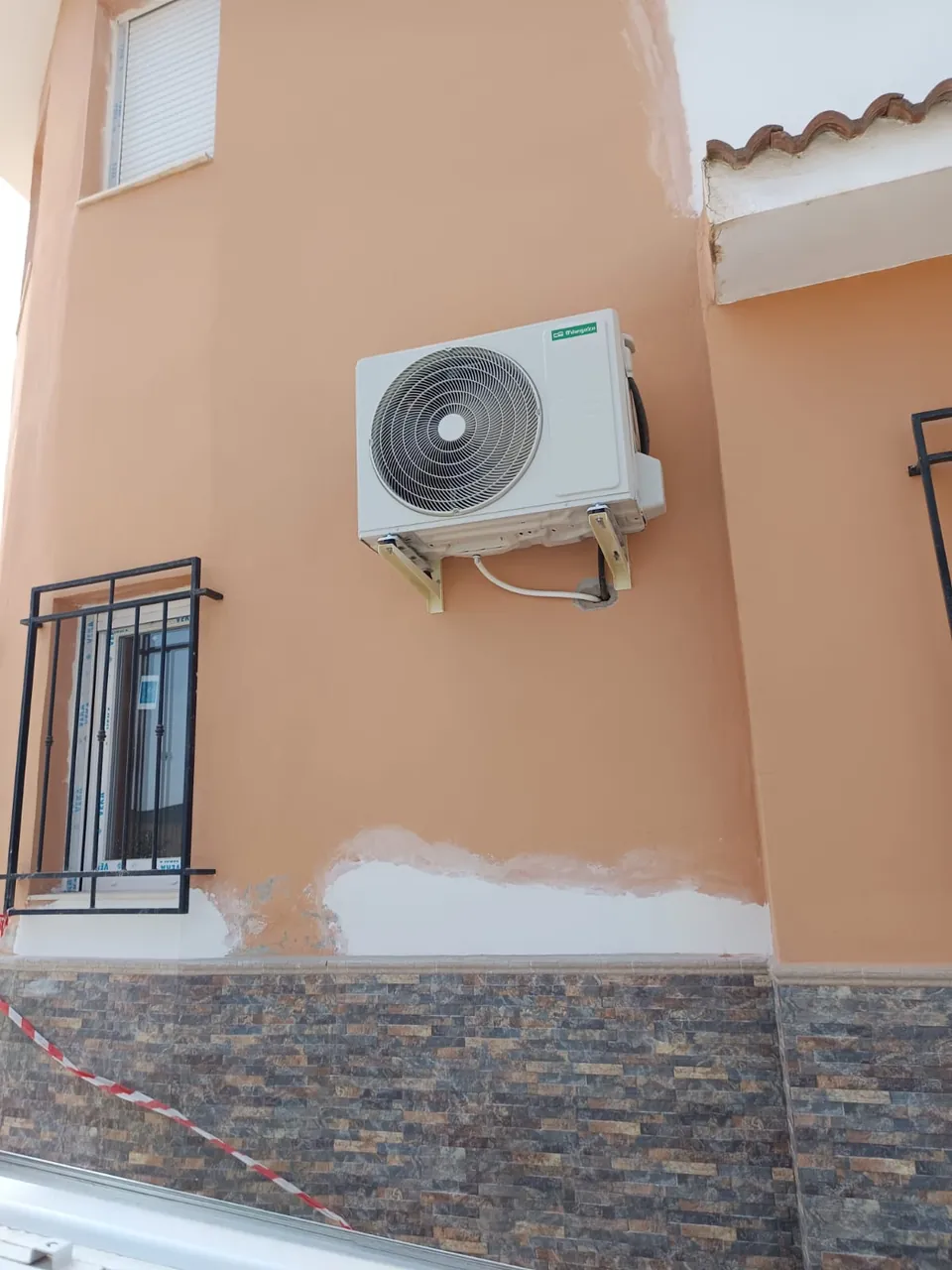 Unidad exterior de aire acondicionado instalada en la fachada de una villa.