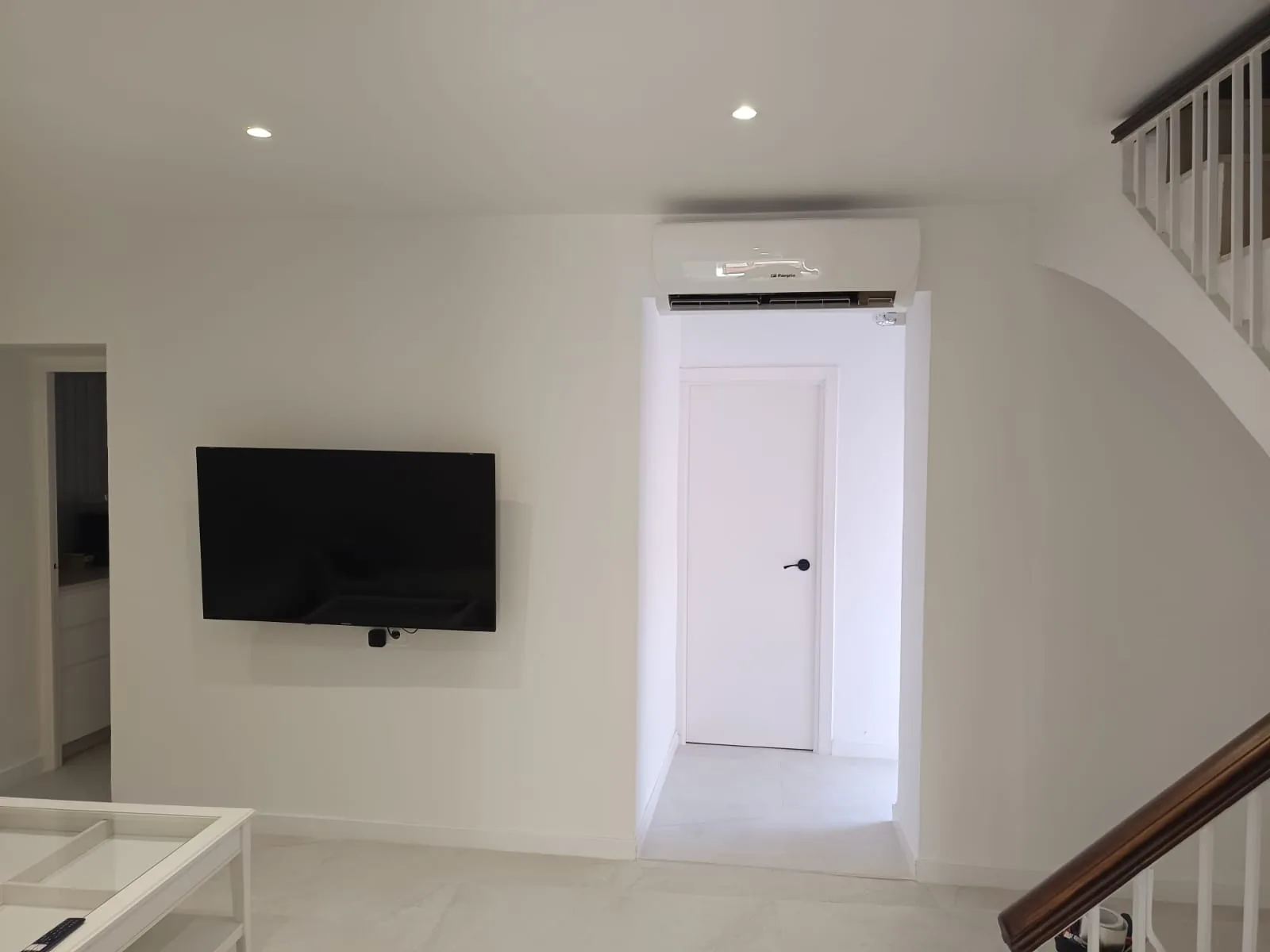 Unidad interior de aire acondicionado montada sobre la puerta de un salón reformado.