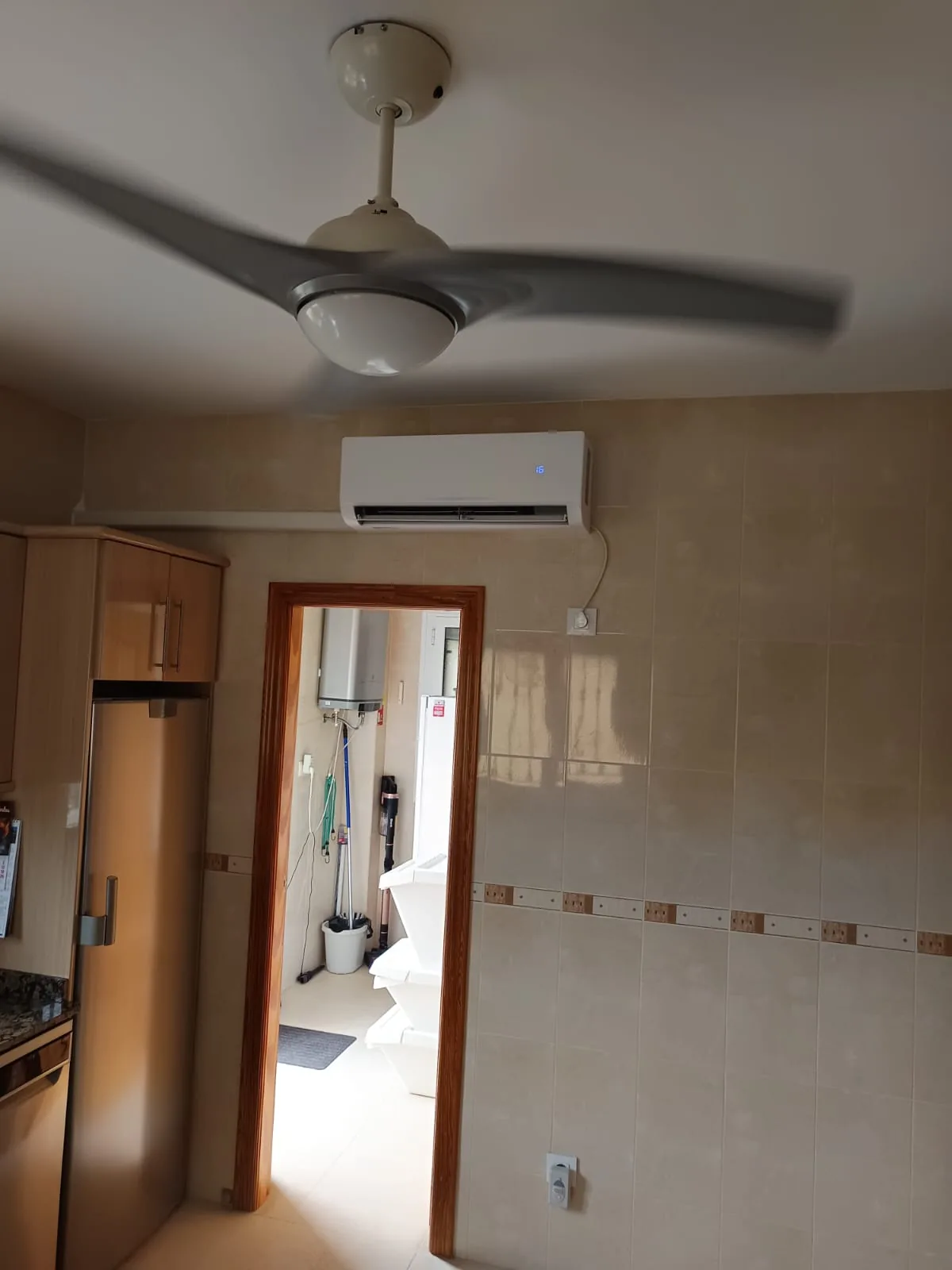 Split de aire acondicionado instalado en la cocina, junto al ventilador de techo.